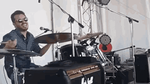 a man is playing drums in front of a microphone .