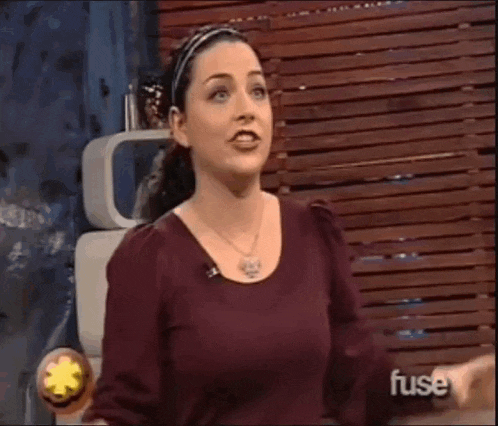 a woman is standing in front of a wooden wall and talking on a television show .