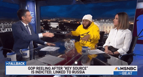 a man and a woman sit at a table on a msnbc news show
