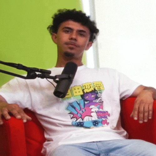 a man wearing a t-shirt that says " spongebob squarepants " sits in front of a microphone