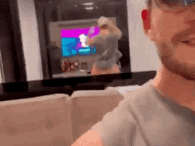 a man is sitting on a couch in front of a television and smiling .