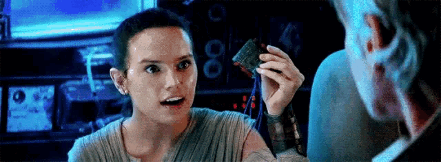 a woman is holding a piece of food and talking to a man in a dark room .