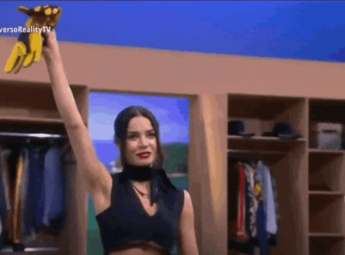 a woman in a black top is holding a stuffed animal in her hand in front of a closet .