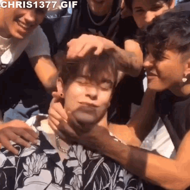 a group of young men are standing around a young man .