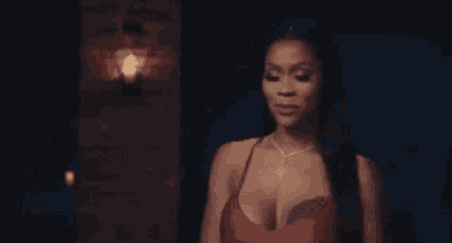 a woman in a red dress is standing in a dark room in front of a light .