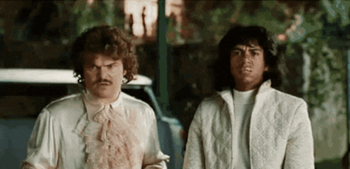 two men are standing next to each other and looking at something .