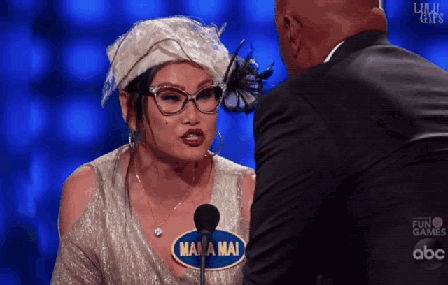 a woman with a name tag that says mama mai stands in front of a microphone