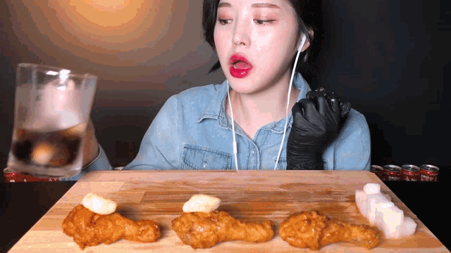 a woman wearing headphones is eating chicken on a wooden cutting board
