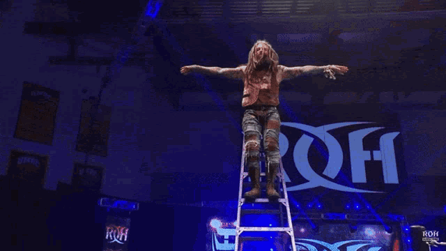 a wrestler is laying on a table in front of a sign that says roh on it