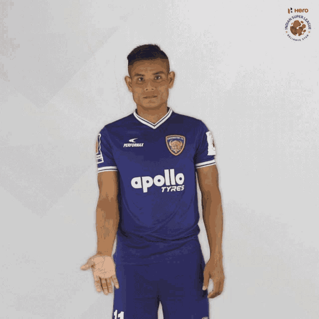 a man wearing a blue apollo tyres jersey stands in front of a white background