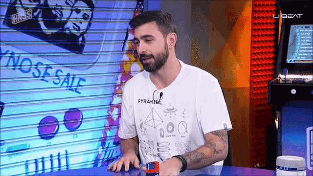 a man with a beard wearing a white t-shirt that says pyramids