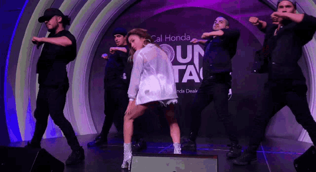a group of dancers perform in front of a sign for cal honda