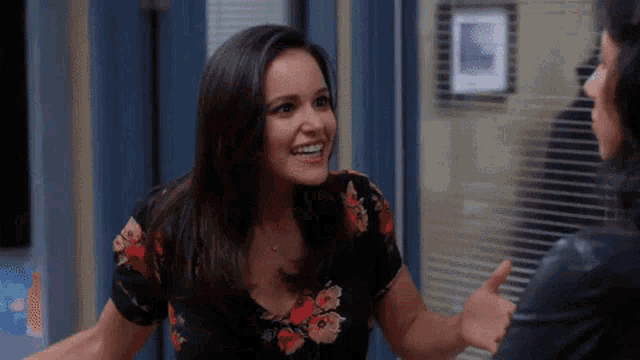 a woman in a floral shirt is talking to another woman in a room .
