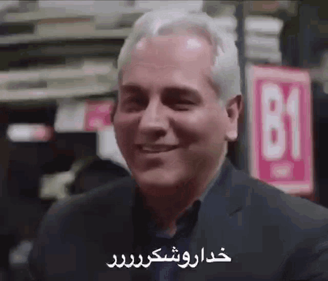 a man in a suit is smiling in a store with a sign that says b1 on it .