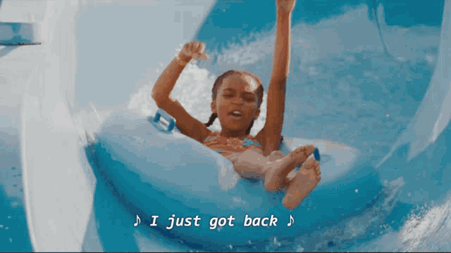 a little girl is riding down a water slide with the words " i just got back " above her