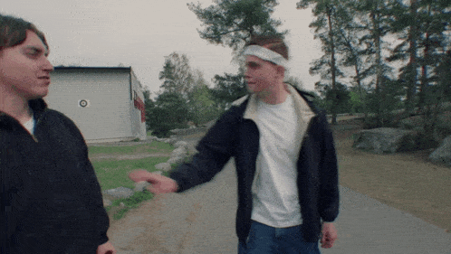 a man with a bandage on his head talks to another man on a path