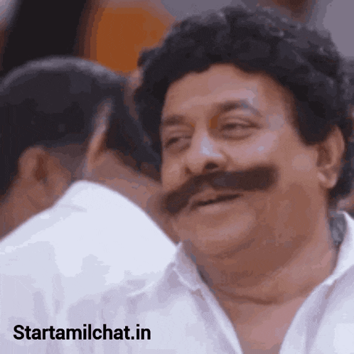 a man with a mustache is smiling and looking at another man