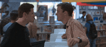 two men are looking at each other in a store and one is wearing headphones
