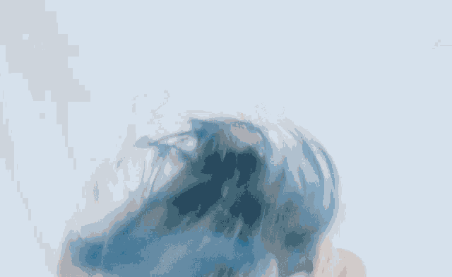a woman with blue hair is laying on a bed with her head in the air .