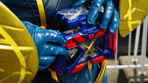a person in a blue and gold costume is holding a blue and red toy
