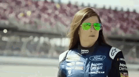 a woman wearing sunglasses and a ford uniform is standing on a track .