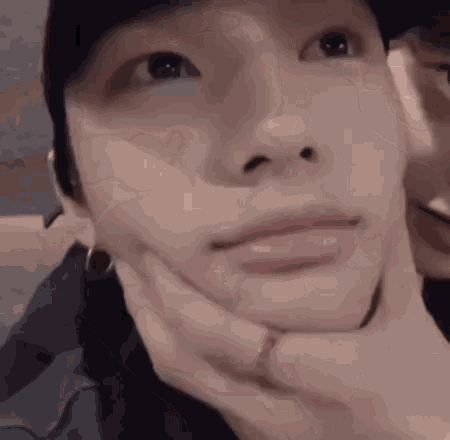 a close up of a person 's face with a hand on it .