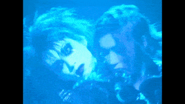 a man and a woman are in a dark room with blue lights