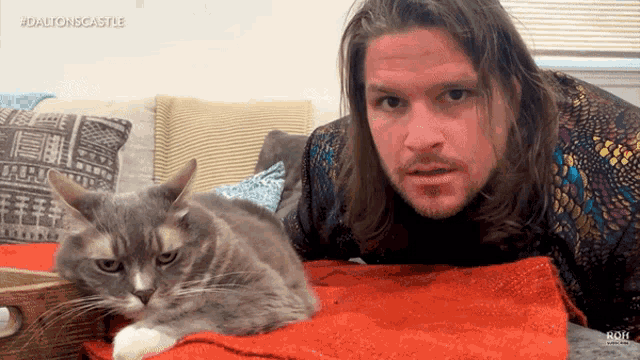 a man laying on a couch next to a cat with the hashtag dalton iscastle on the bottom