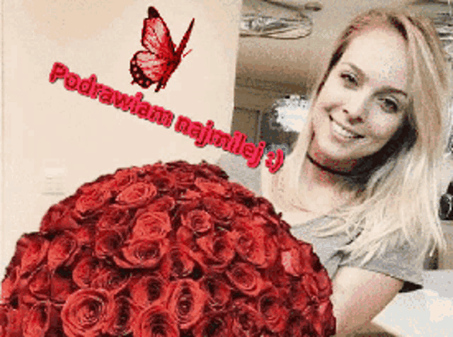 a woman holding a large bouquet of red roses with a butterfly in the background that says " podrywiam najmilej "