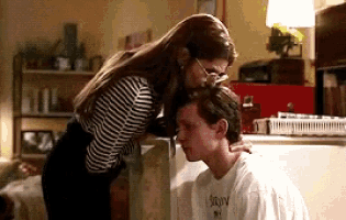 a woman is kissing a man 's forehead in a kitchen in front of a refrigerator .