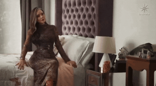 a woman in a leopard print dress is sitting on a bed