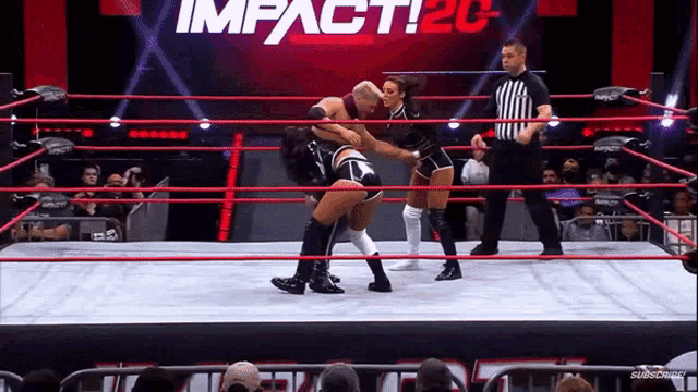 two women are wrestling in a ring with a referee in front of a sign that says impact20