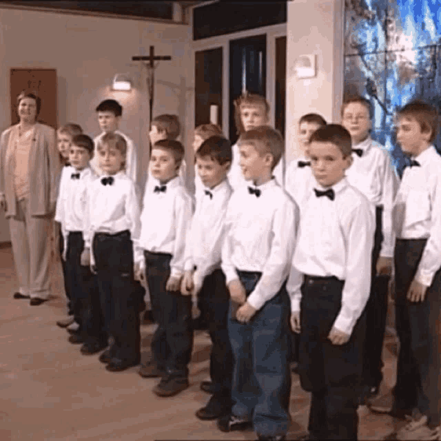 a group of young boys in white shirts and bow ties are standing in a line