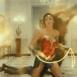 a woman in a wonder woman costume is kneeling on the floor holding a whip