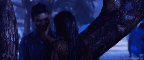 a man and a woman are hugging each other in front of a tree .