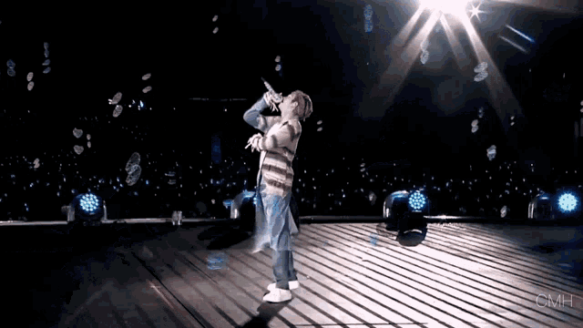 a person is singing into a microphone on a stage and the word omh is on the bottom