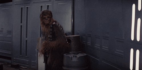 a chewbacca is standing in a room with a trash can