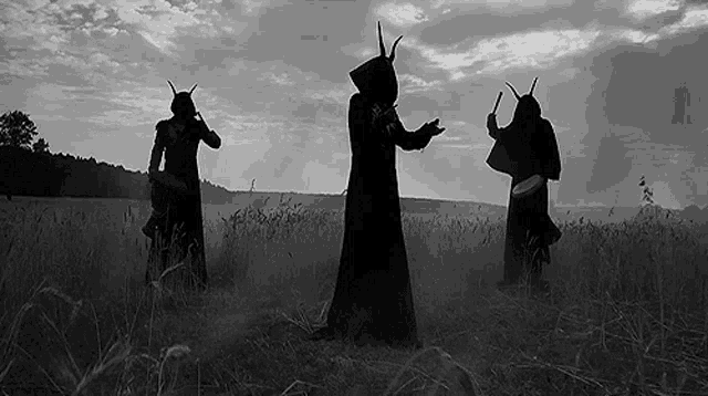 three people with horns are standing in a field in a black and white photo