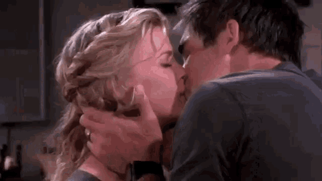a man and a woman are kissing in a kitchen in a close up .
