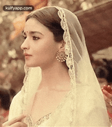 a close up of a woman wearing a white dress and veil .