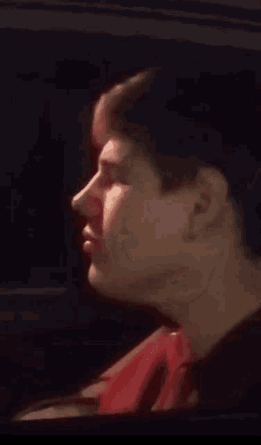 a close up of a man 's face in a car looking out the window .