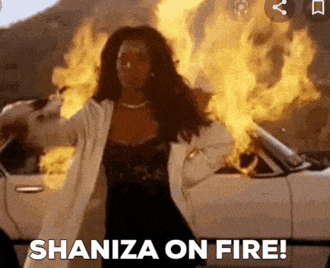 a woman is standing in front of a car that is on fire and says ' shaniza on fire ! '