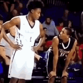 two basketball players are talking to each other on the court .
