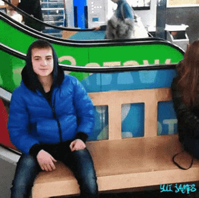 a man in a blue jacket is sitting on a wooden bench