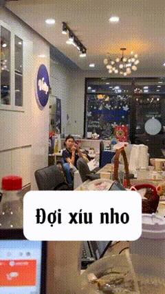 a woman sits at a table in a room with a sign that says doi xiu nho on it