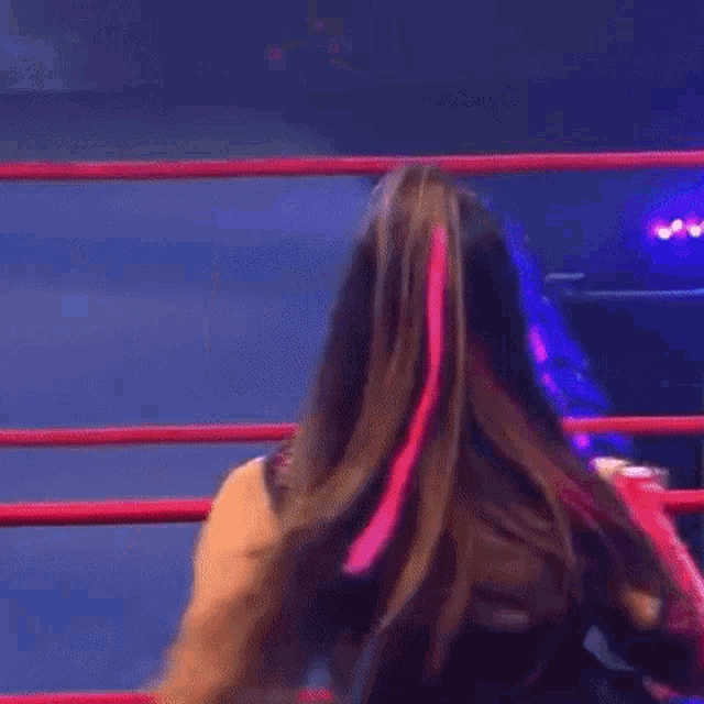 a woman is sitting in a wrestling ring with her hand on her mouth .