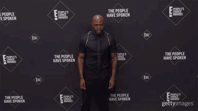 a man stands in front of a wall that says " the people 's choice awards "