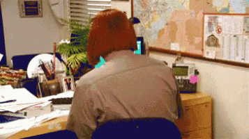 a man sits at a desk in front of a bulletin board with a map on it