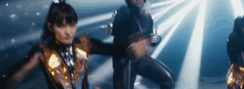 a group of people are dancing in a dark room with lights shining on them
