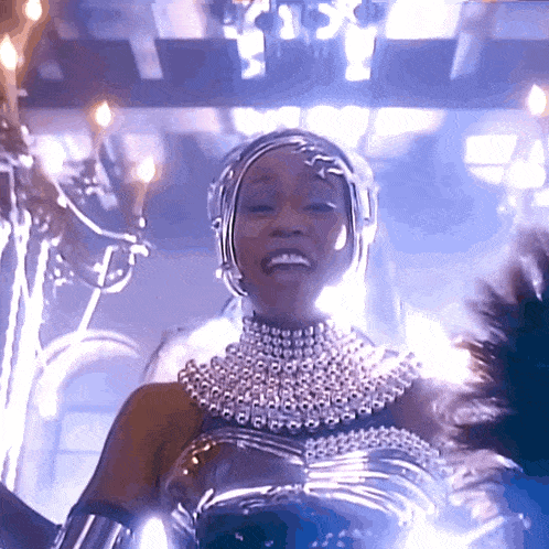 a woman in a silver outfit is smiling and dancing